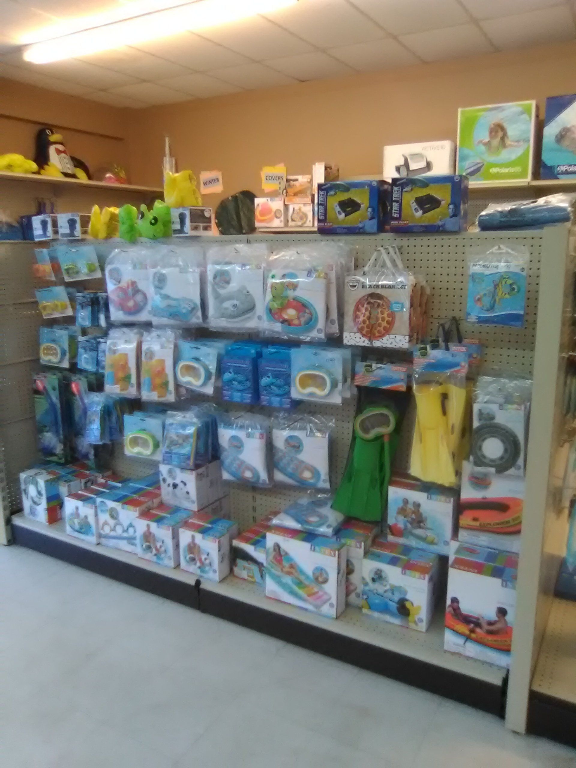 Shelves filled with swimming pool floats and accessories in a store.