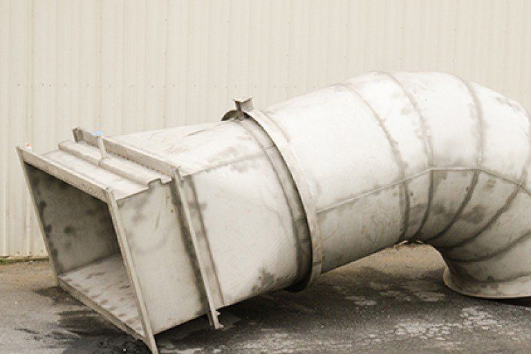 A large white pipe is sitting on the ground in front of a building.