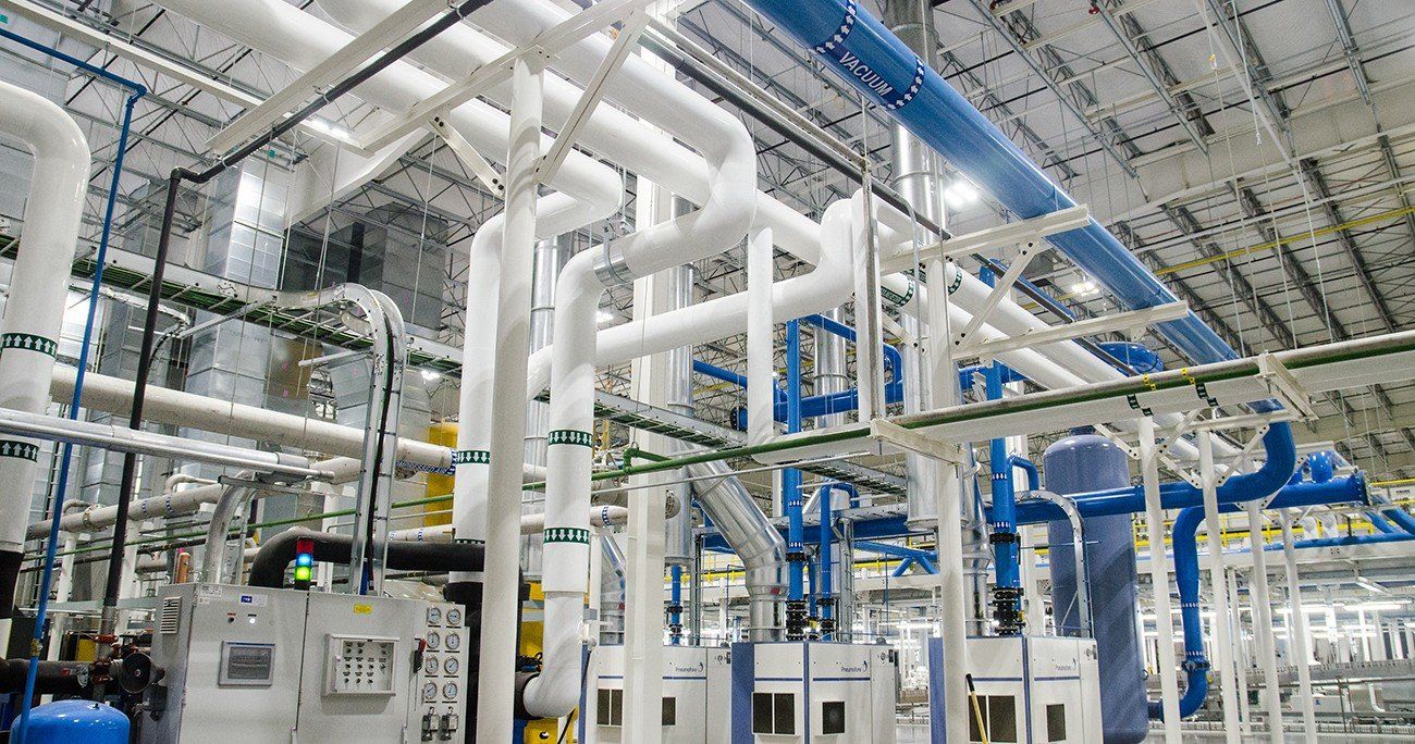 Industrial interior with complex network of white and blue pipes.