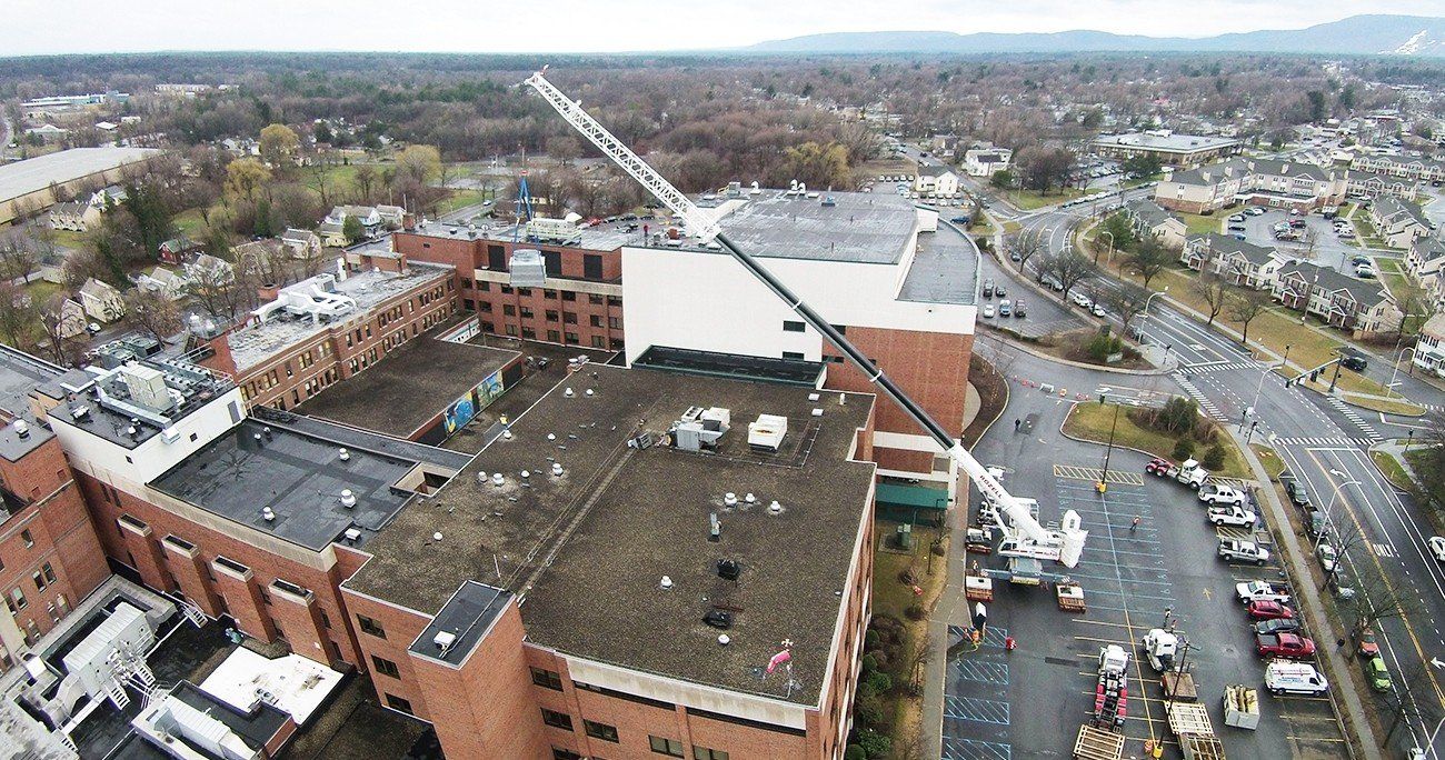 Aerial view of a hospital building with a crane; construction happening on the roof.
