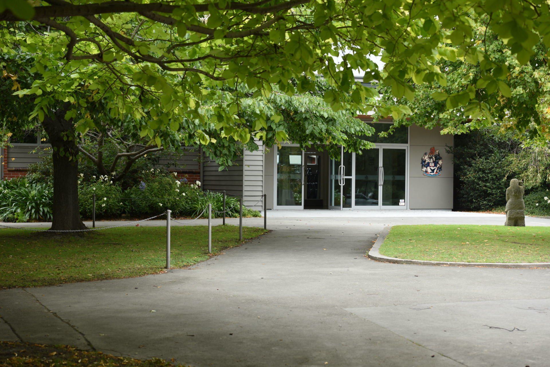 A building with a clock on the side of it is surrounded by trees and grass.
