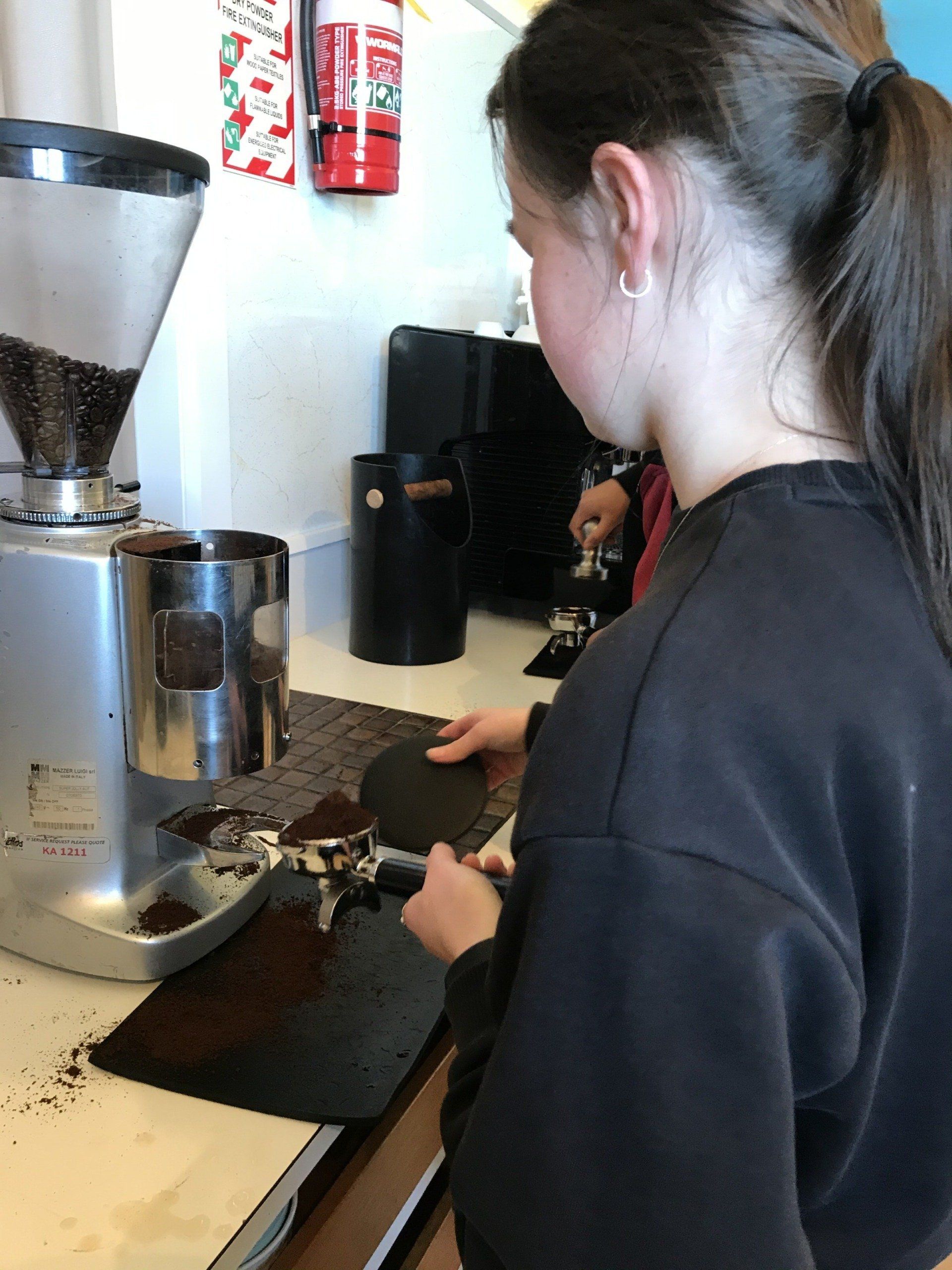 Timaru Girls Hig School | A woman is grinding coffee beans in a coffee shop