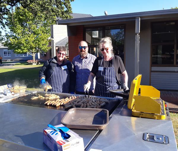 A group of people are standing around a grill cooking food