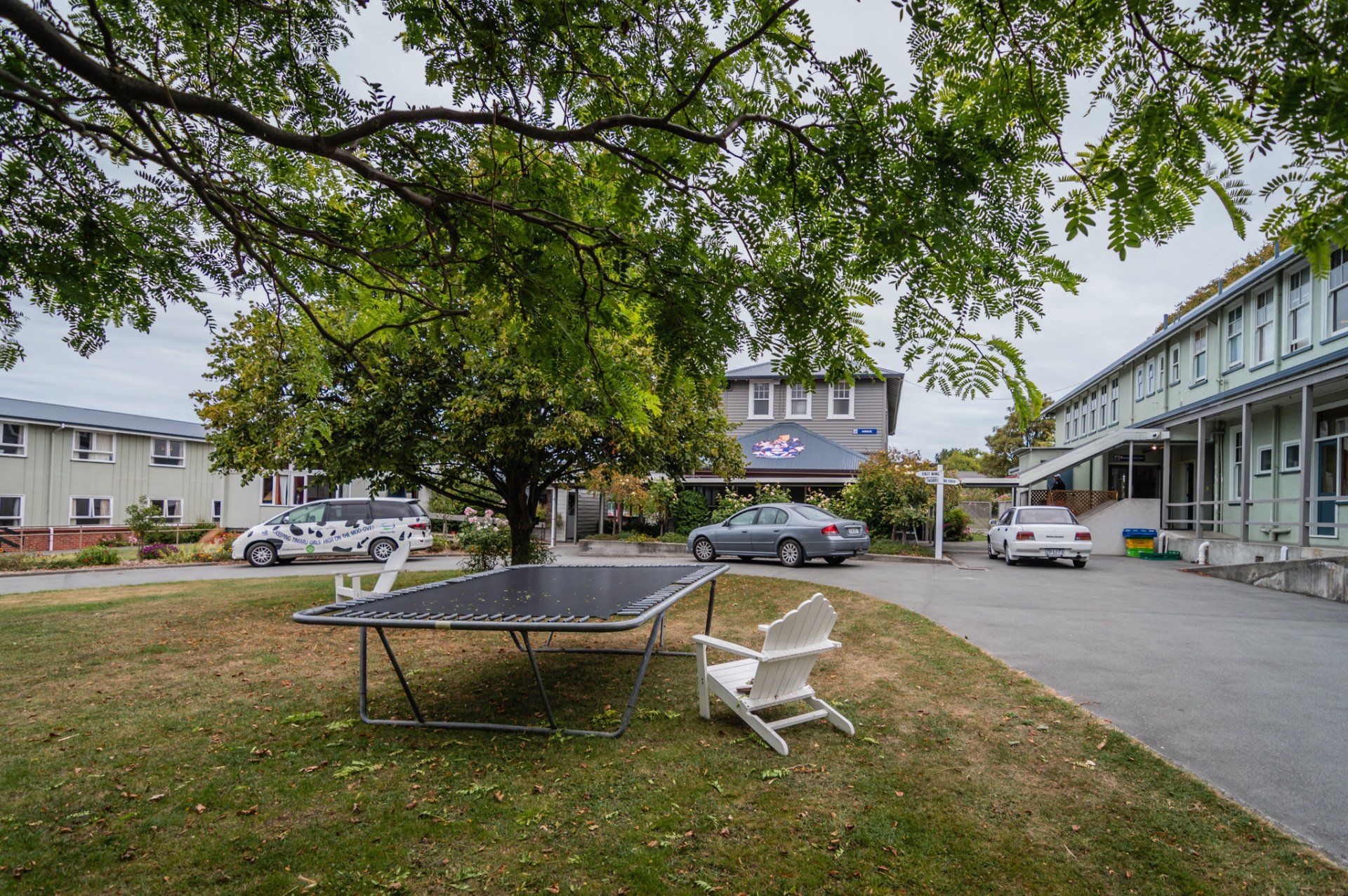 A trampoline is sitting in the grass in front of a building.