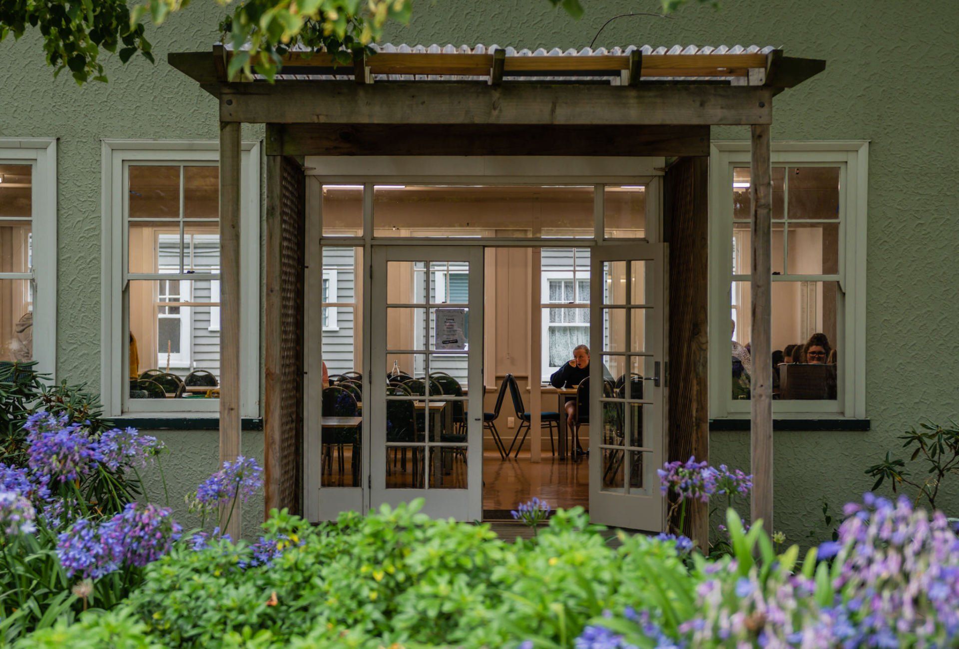 Timaru Girls Hig School | A man is sitting at a table in a room with a porch.