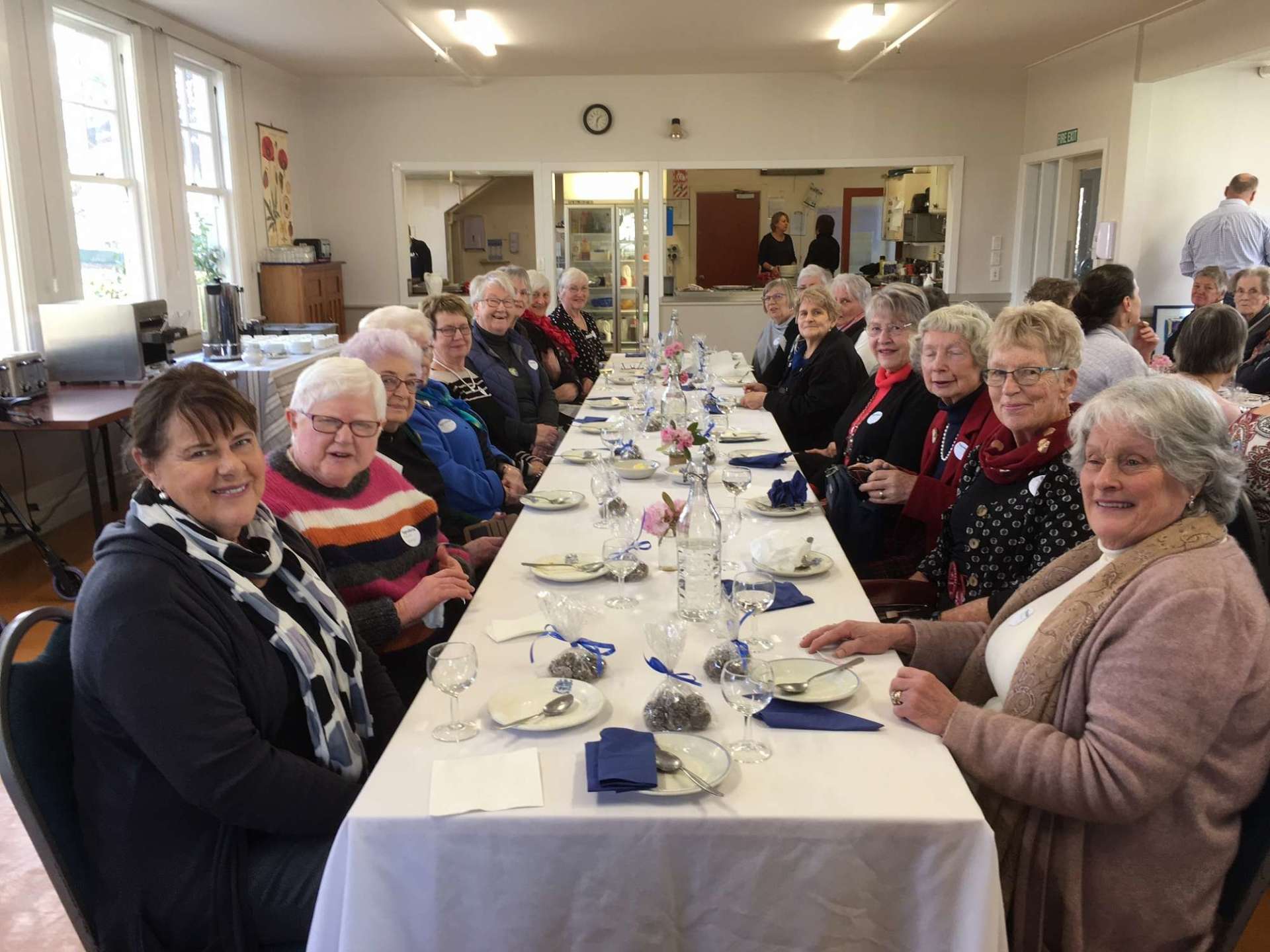A group of people are sitting at a long table in a room.