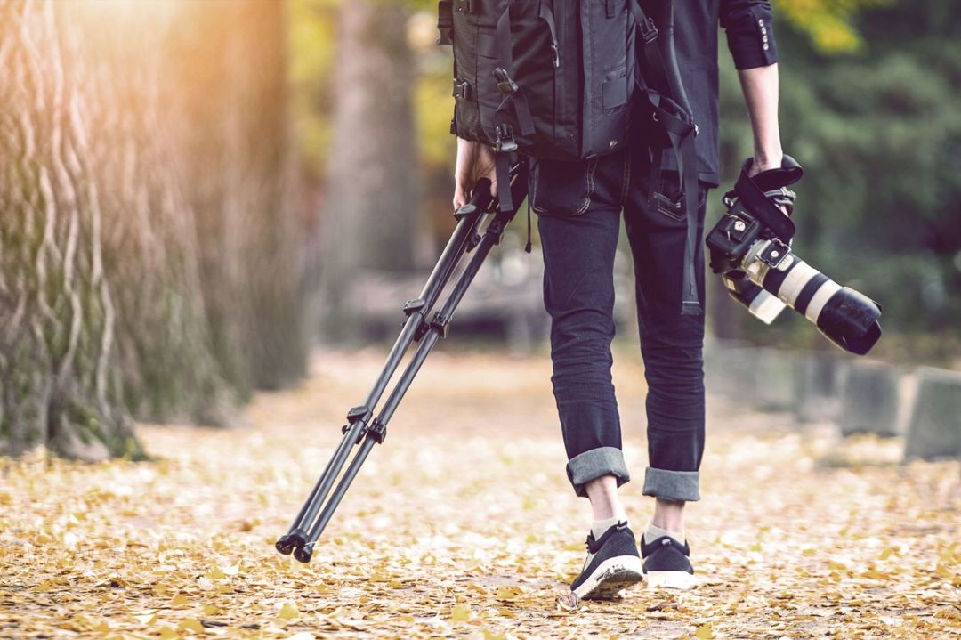 fotografa con macchina fotografica e cavalletto in mano