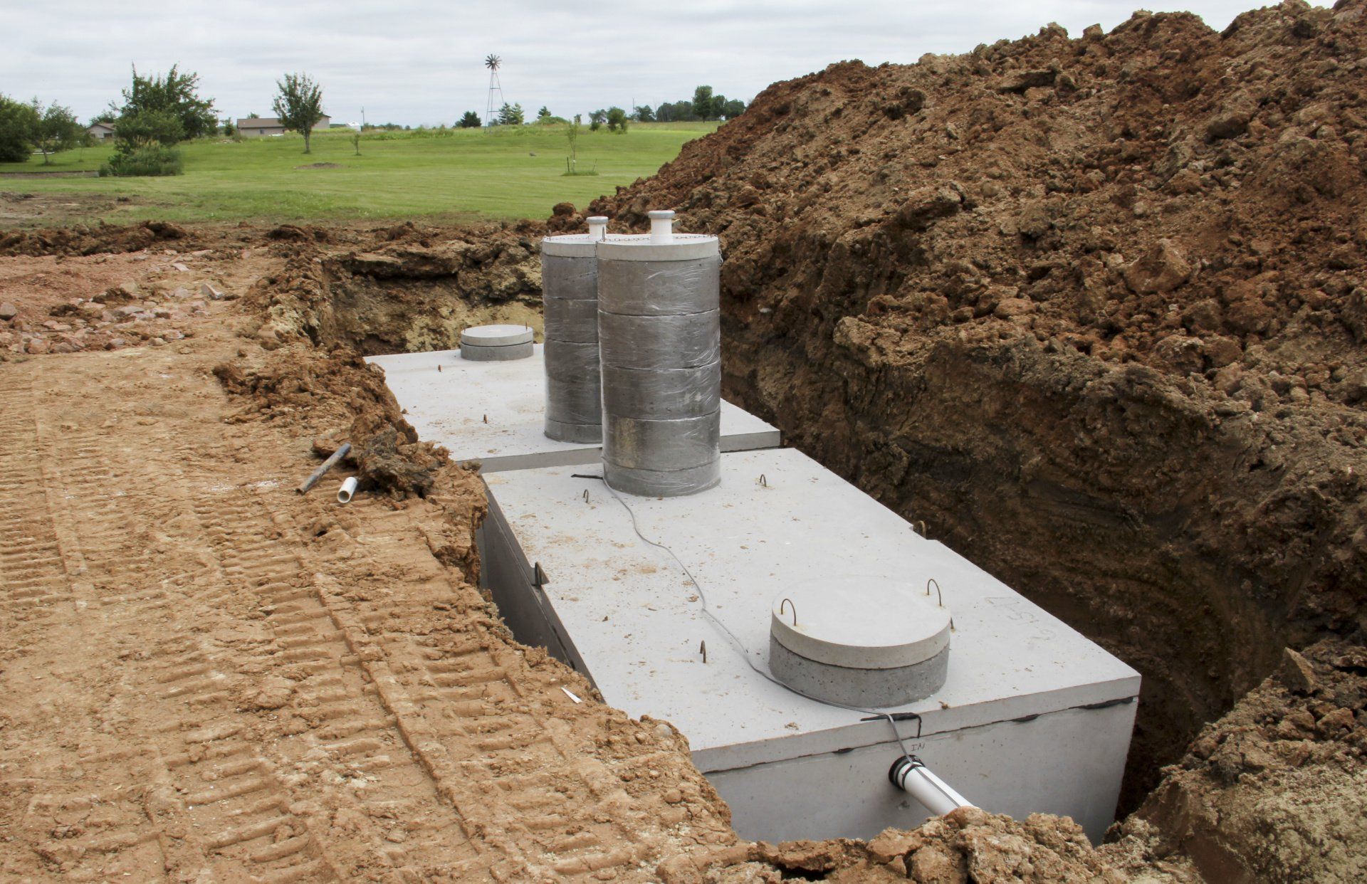 Concrete septic tank installed in a dirt trench at a construction site