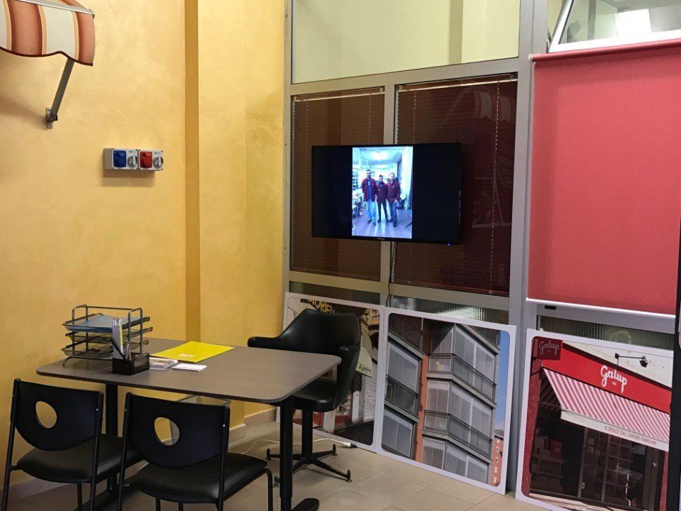 Spazio ufficio con tavolo, sedie, TV con foto e poster.