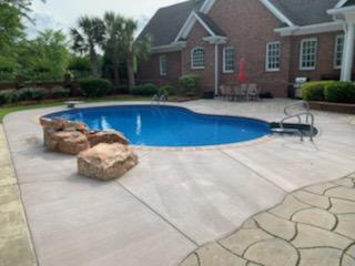 inground pool with rock formation and diving board