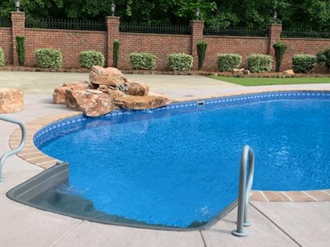 inground pool with rock formation and stairs