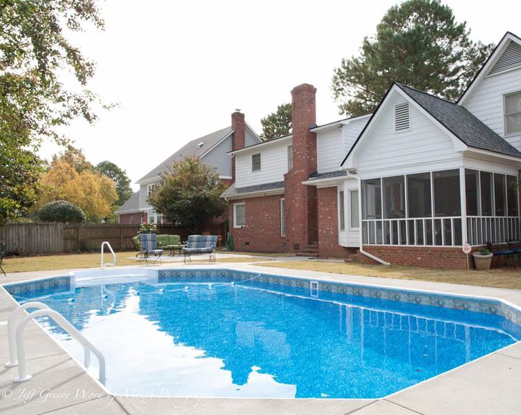 inground pool and back of house with a screened porch