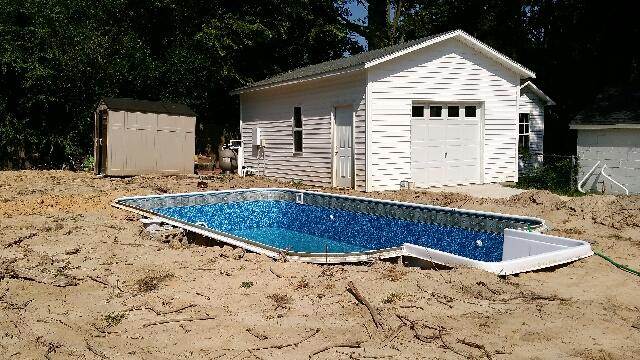 inground pool under construction with garage in background