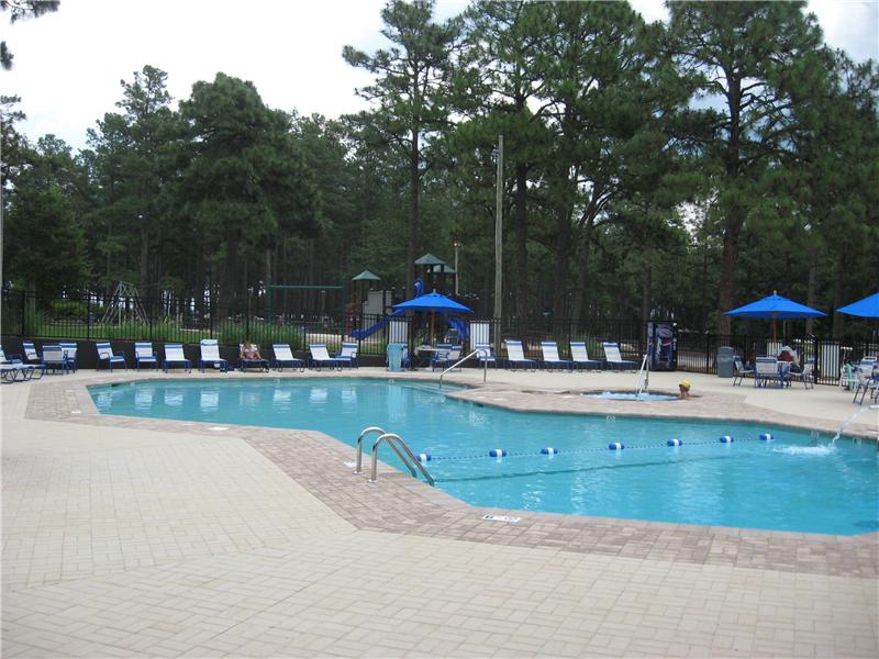 inground pool with brick surround and rows of  lounge chairs