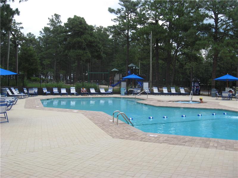 inground pool with brick surround and row of lounge chairs