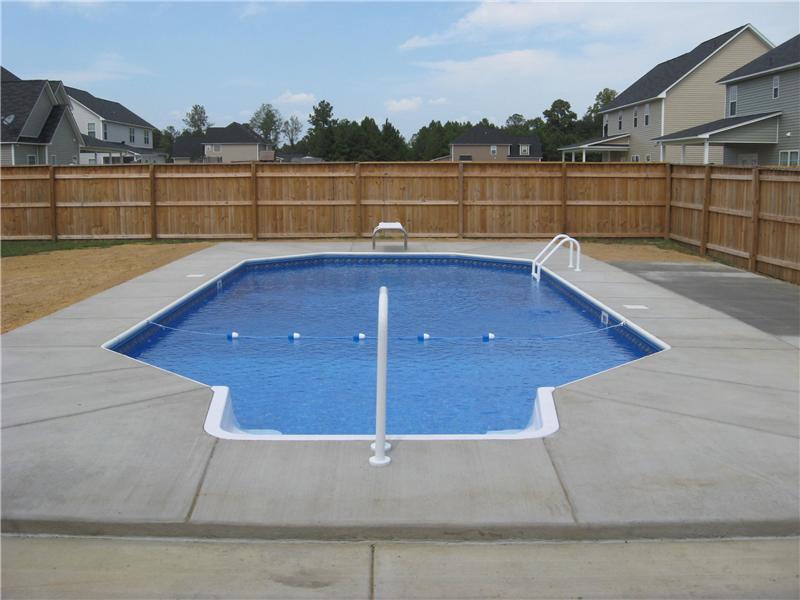 stairs leading into inground pool with cement surround