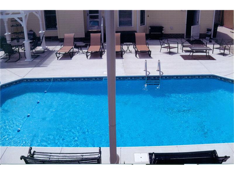inground pool with cement surround and row of lounge chairs