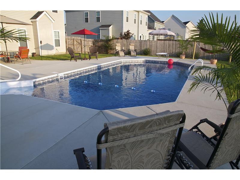 inground pool with cement surround patio sets and lounge chairs