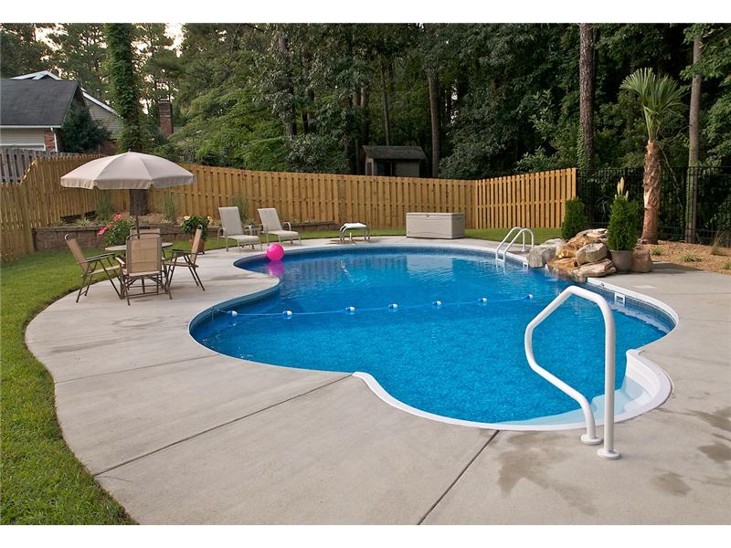 free form pool with patio set and lounge chairs