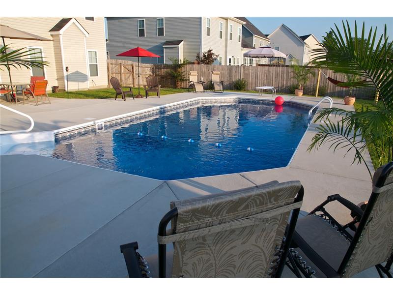 inground pool with pink ball floating and chairs on decking