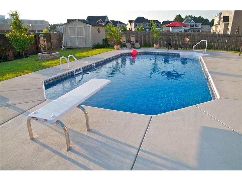 side angle of diving board with pink ball floating in pool