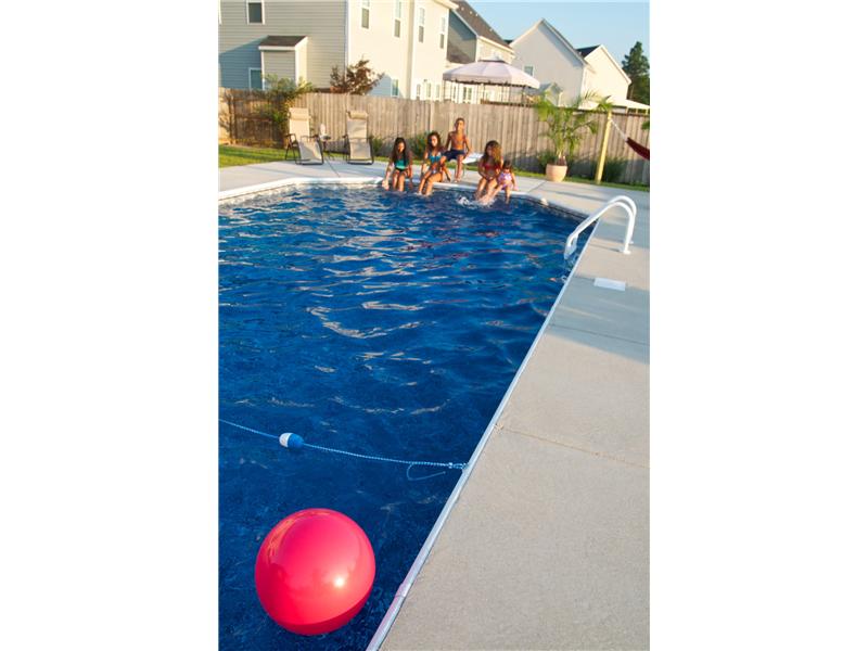 pink ball floating in pool with kids sitting on the edge