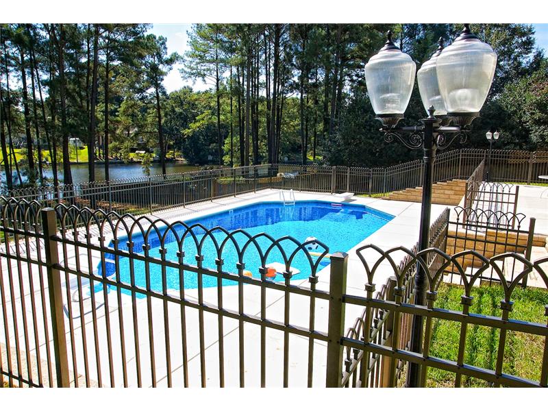 wrought iron fence with lamp post and pool in background