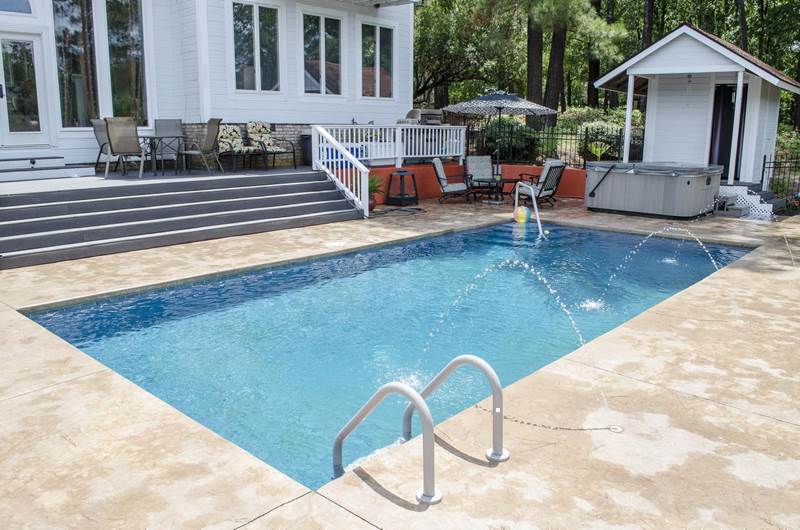 small rectangular pool with hot tub on decking
