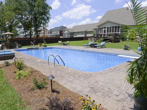 rectangular pool with lounge chairs on surrounding decking