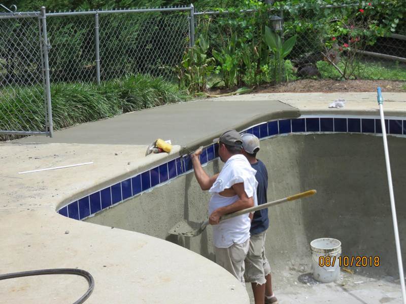 2 workers retiling inground pool
