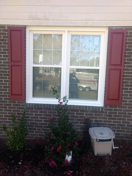double window with red shutters on brick house