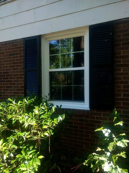 single window with black shutters on brick house