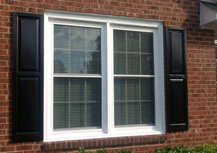 double window with black shutters on brick house