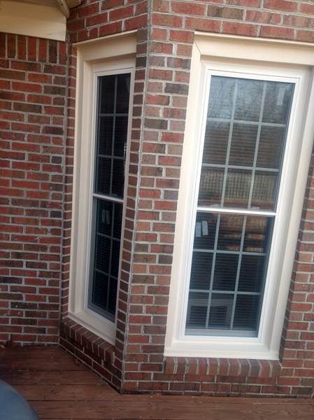 2 single windows one on each corner of brick house
