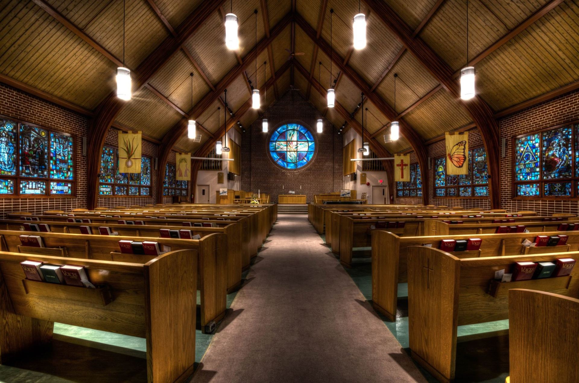 the inside of Thornhill church with wooden benches and stained glass windows .