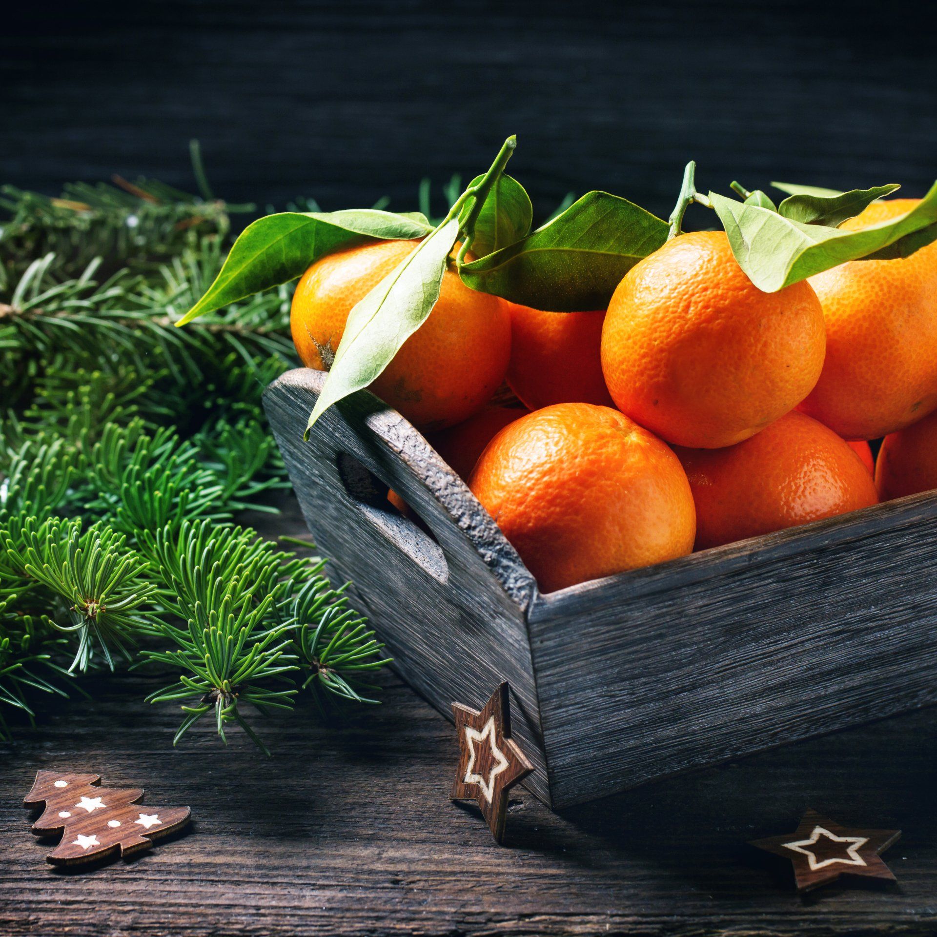 a wooden box filled with oranges and leaves on a wooden table .