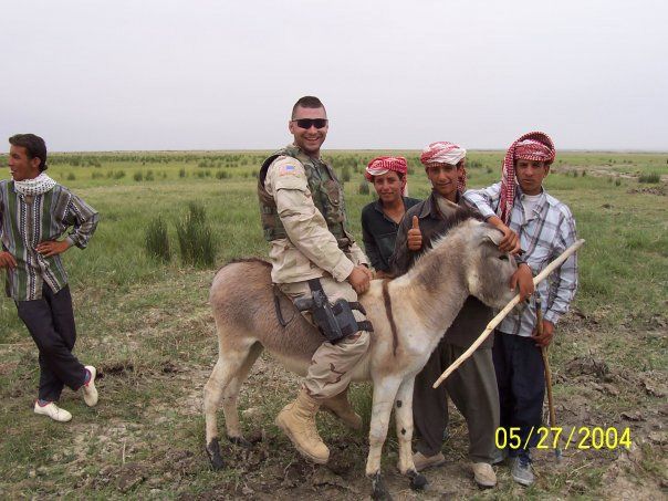 Soldier on donkey poses with local children in a field, May 27, 2004.