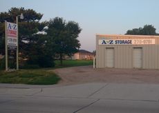 A small, beige A-Z Storage building and a tall sign with the same name, set by a tree-lined grassy lot at dusk.