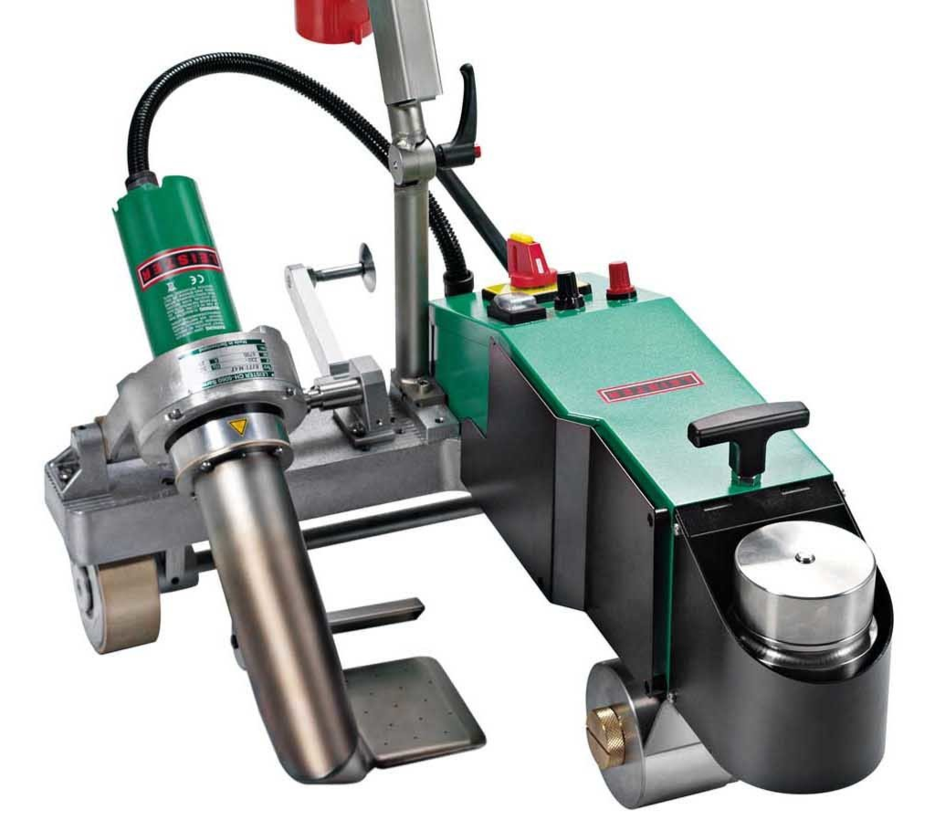 Industrial floor-cleaning machine with green and gray body, metal handle, and brushes on wheels