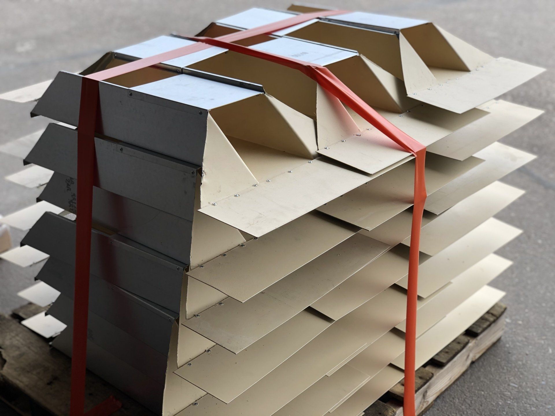 Stacked cardboard sheets strapped with red bands on a pallet in a warehouse