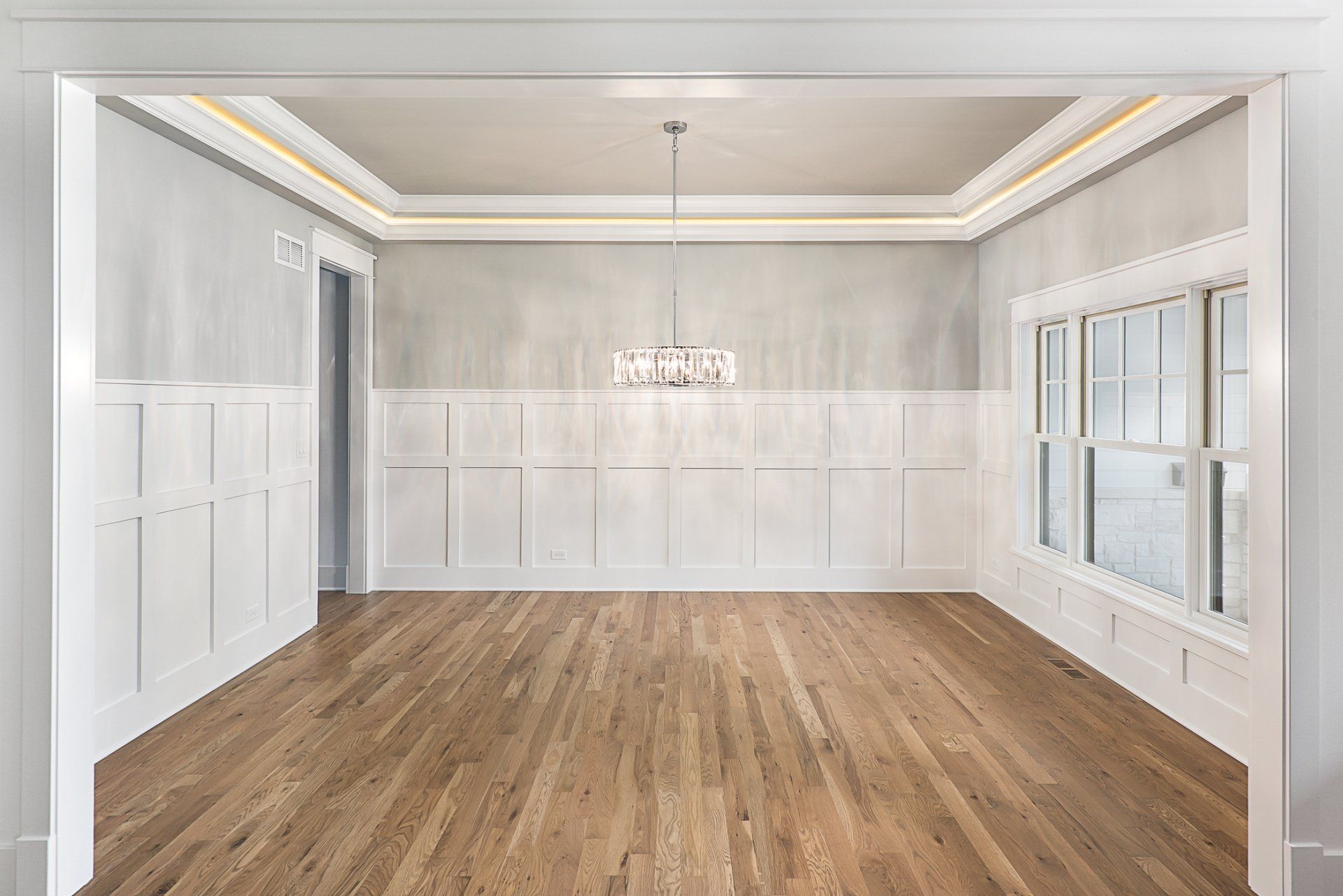 An empty dining room with hardwood floors and white walls.