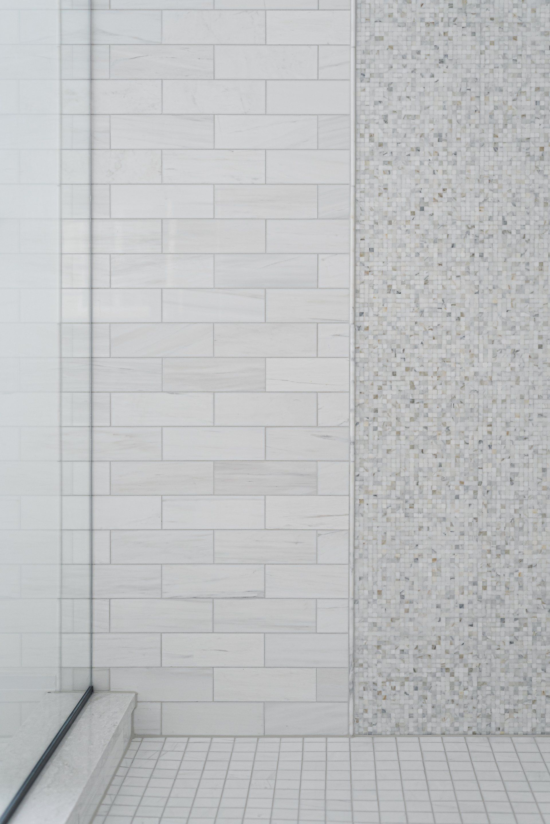 A bathroom with white tiles and a walk in shower.