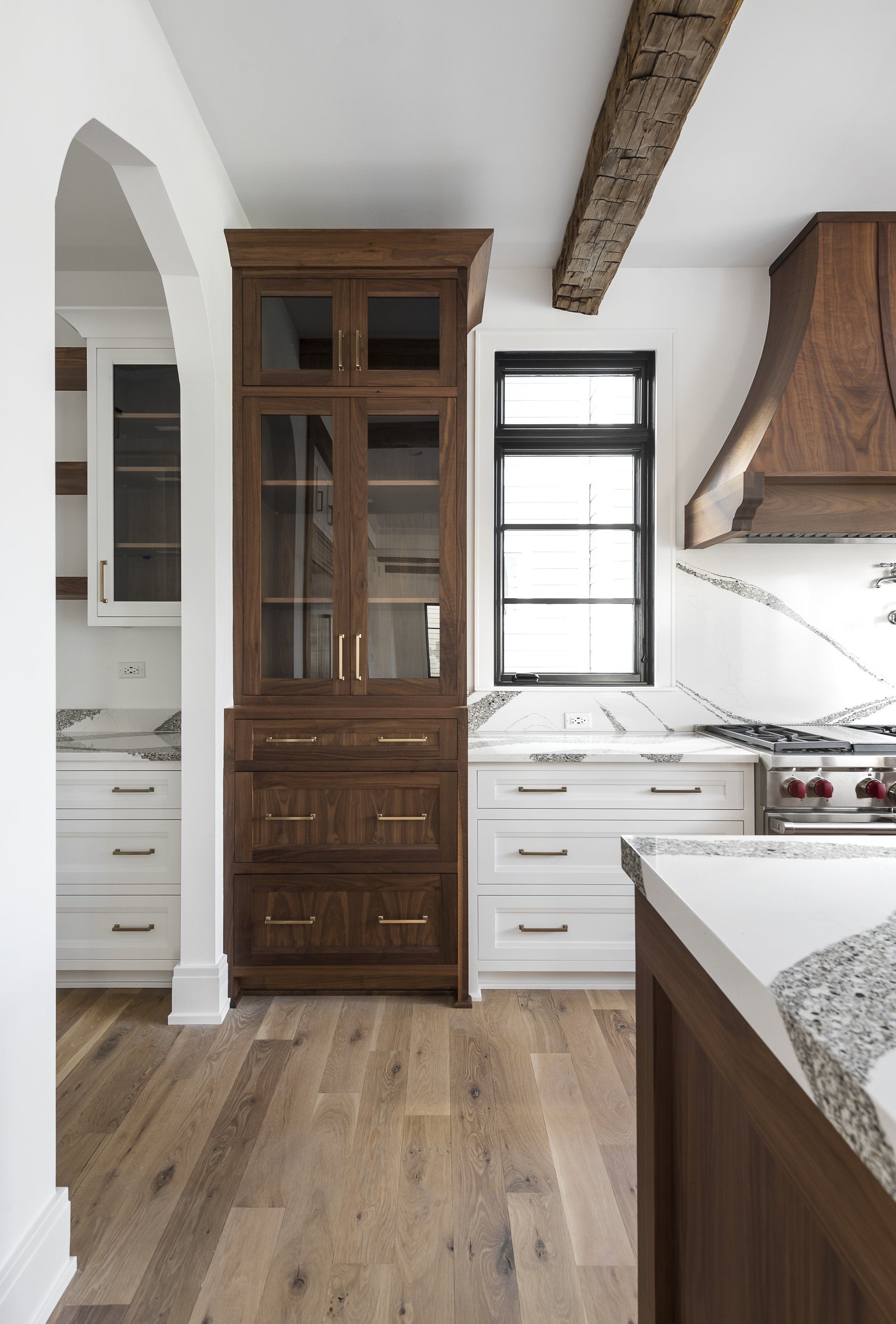 A kitchen with wooden cabinets , a stove , and a window.