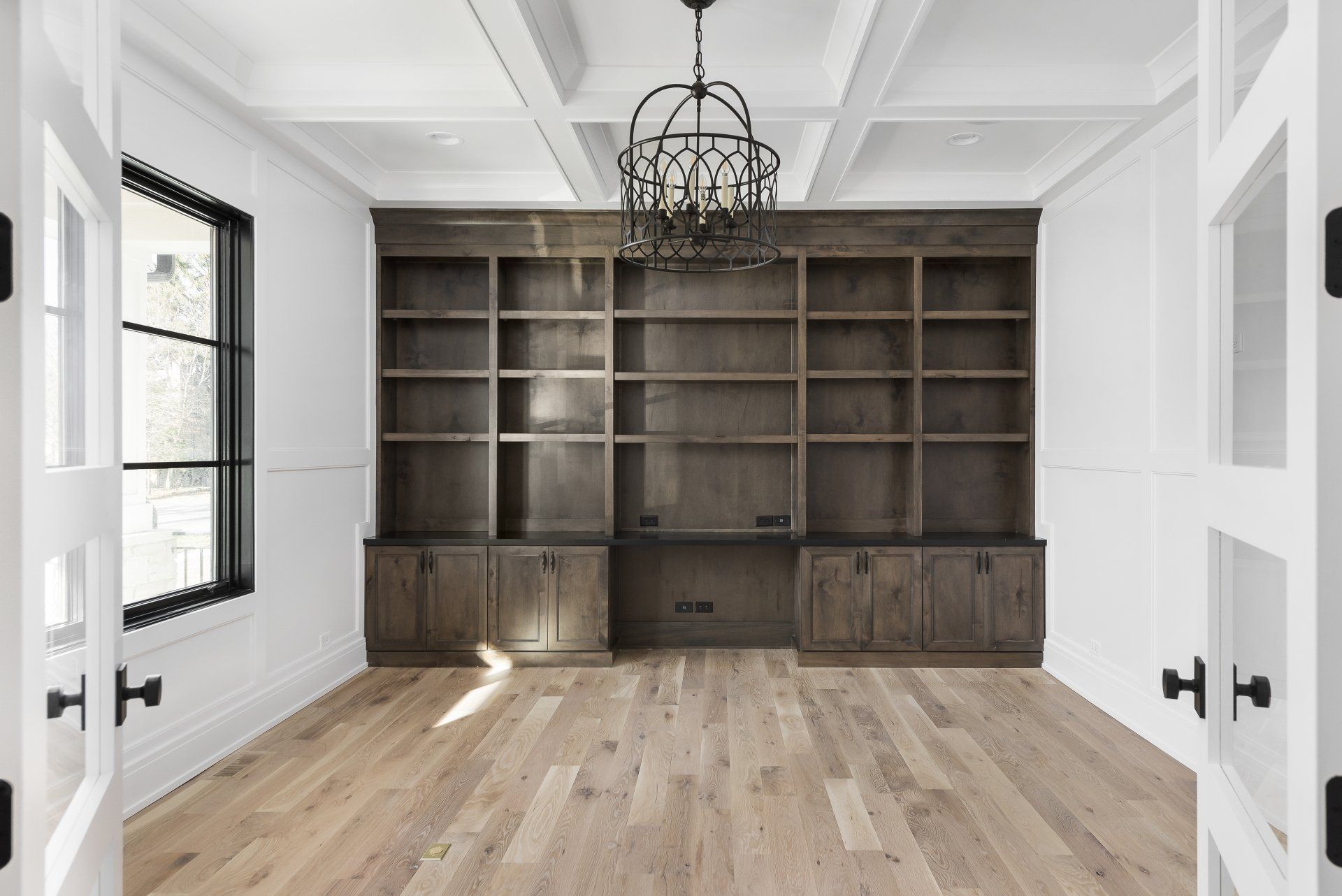 A large empty room with wooden shelves and a chandelier.