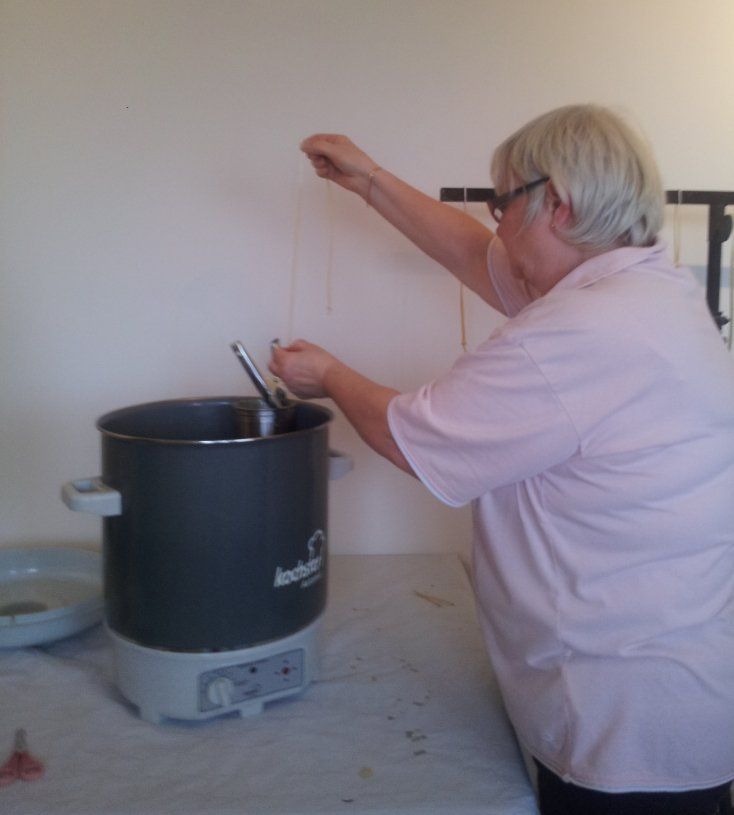 Dipping wicks into melted beeswax to make tapered candles
