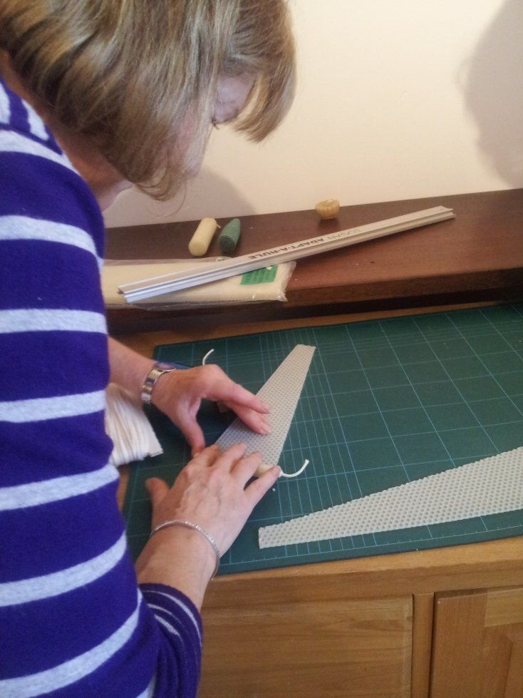rolling sheets of cut beeswax to make tapered candles