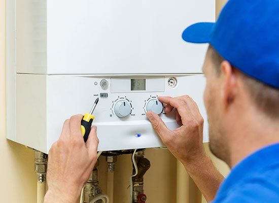 Worker Fixing Heater — Hatfield, MA — AM/PM Plumbing & Heating Worker Fixing Heater — Hatfield, MA — AM/PM Plumbing & Heating