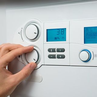 Commercial Water Heaters — Person Adjusting Room Heat in Clute, TX Commercial Water Heaters — Person Adjusting Room Heat in Clute, TX