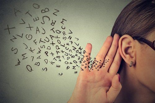 Mettendo la mano all'orecchio per sentire meglio
