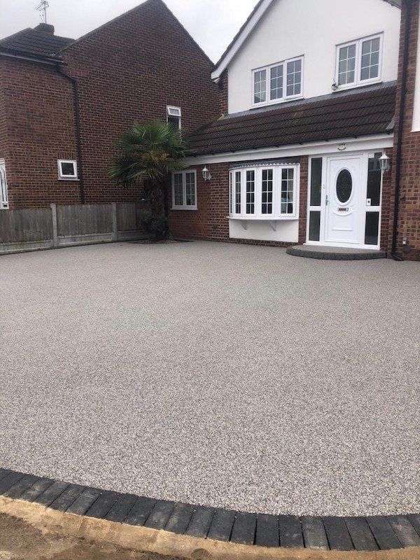 A sweeping resin bond driveway in front of a white house